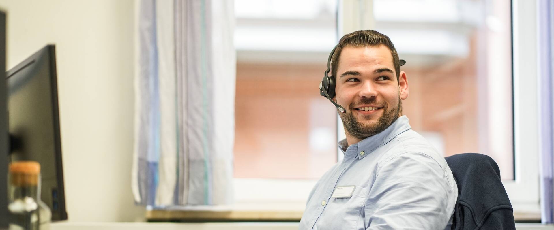 Freundlicher junger Mann sitzt im Büro aus dem Geschäftsbereich der IT