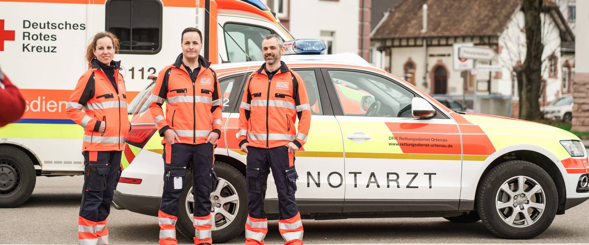 Drei Notfallsanitäter stehen vor ihrem Einsatzwagen
