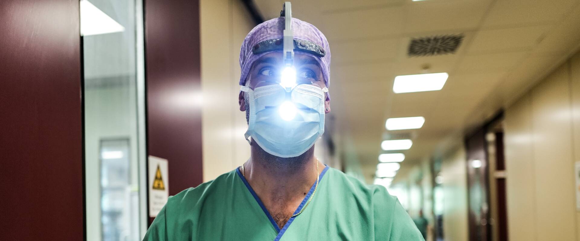 Arzt mit Stirnlampe und OP-Maske im Flur