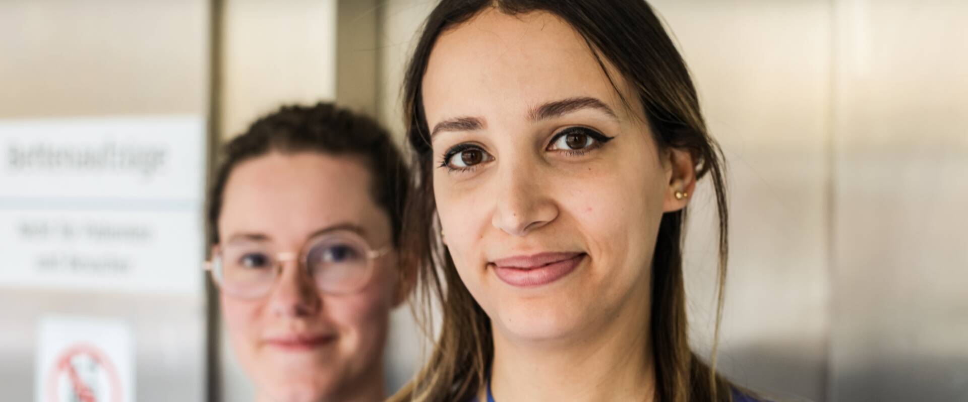 Zwei junge Frauen stehen vor dem Aufzug
