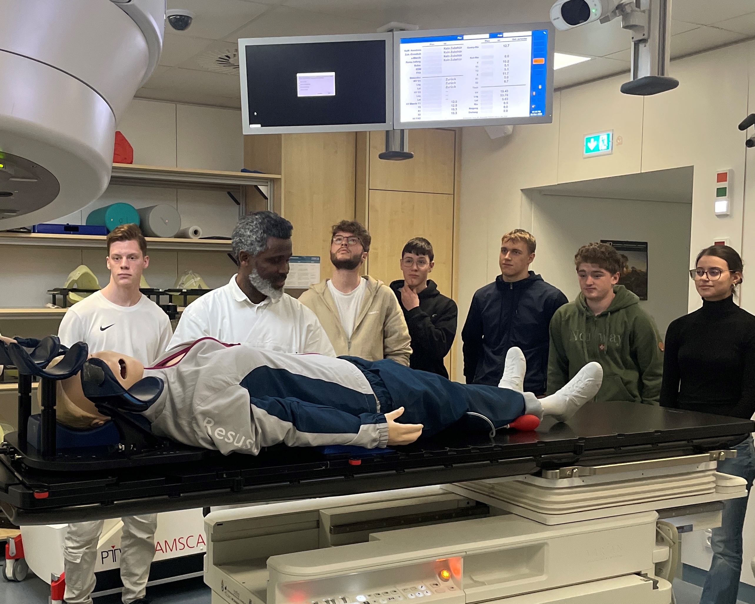 Leitender Medizinphysikexperte Ernest Okonkwo (2. v.l.) erklärt den Schülern am Beispiel des Elektronenbeschleunigers der Abteilung die Funktionsweise von medizinischen Großgeräten bei der Strahlentherapie. 